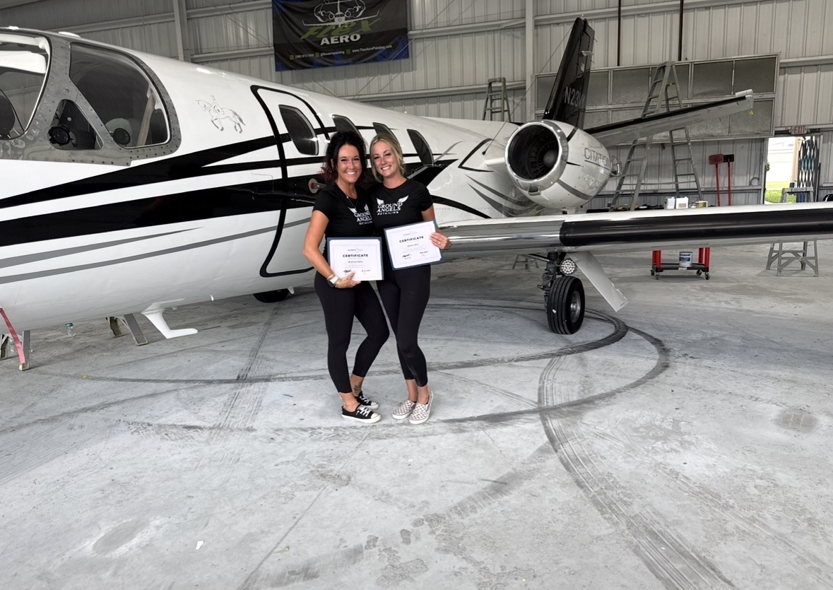 Kristina and Alissa with System X certificates in front of a jet